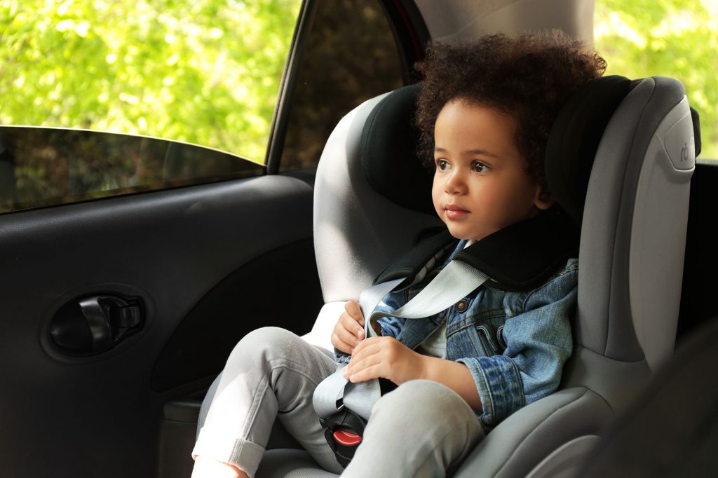 Kind sitzt im Kindersitz im Auto mit offenem Fenster